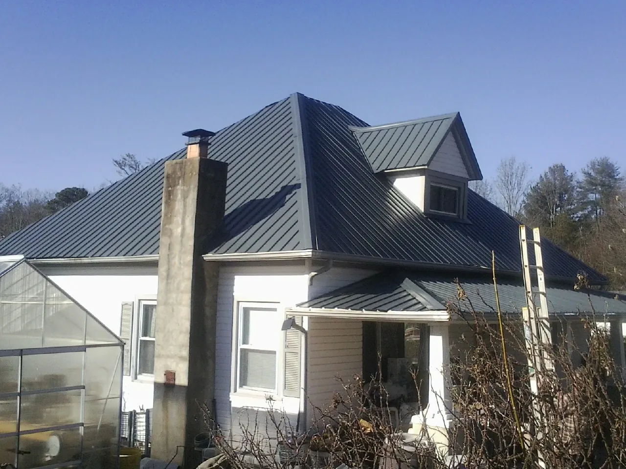 Dark blue standing seam metal roof on a white farmhouse with dormer — Slate & Tile Roof Repair by Roofing Brothers in Paw Paw