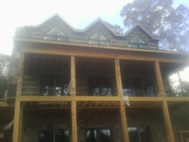 Dormers and porch framing on a large log home under construction — Roof Coating work by our crew in Paw Paw
