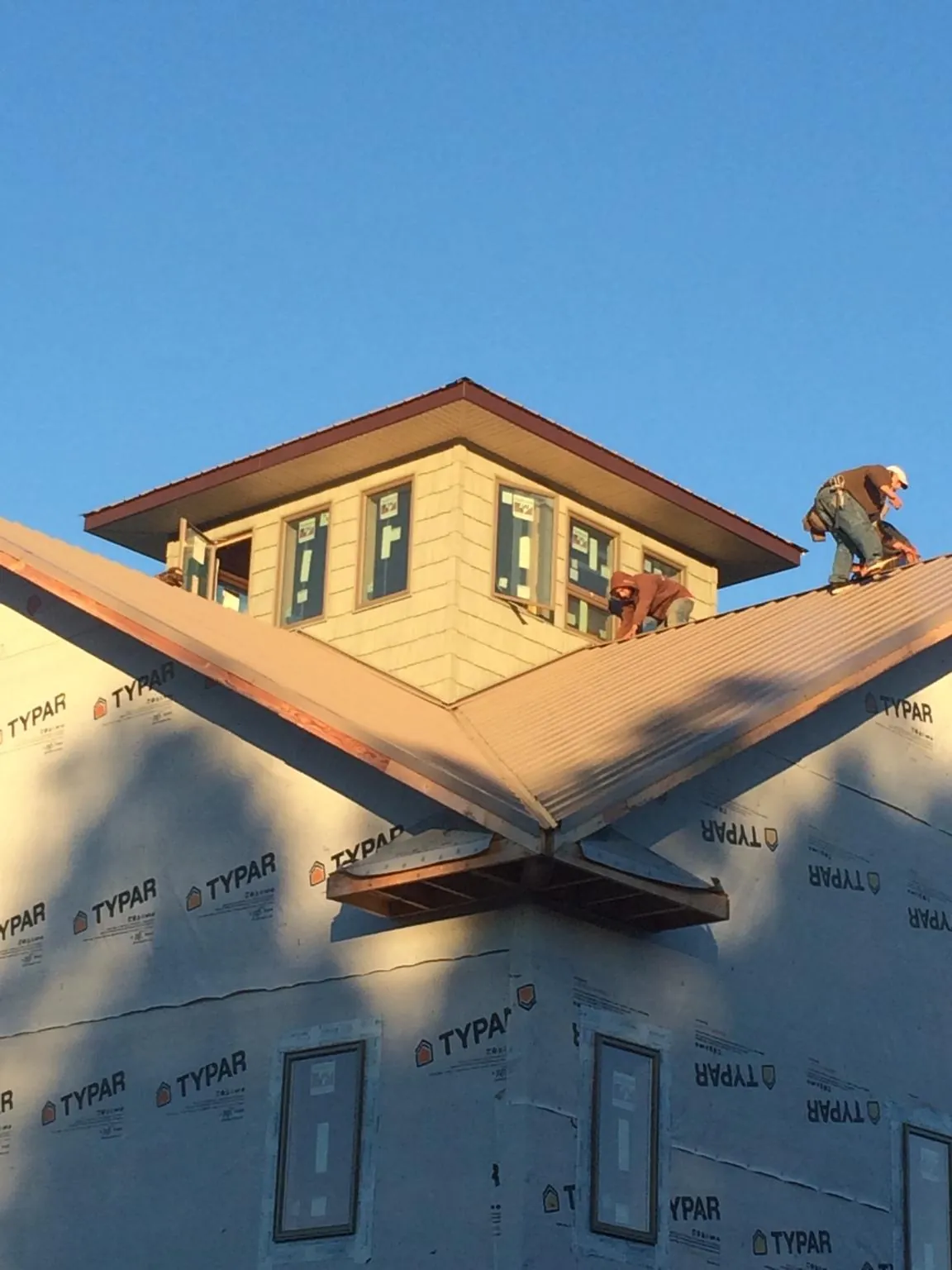 Roofers working around a rooftop cupola on a new metal roof at sunset — Roof Waterproofing in Paw Paw by Roofing Brothers